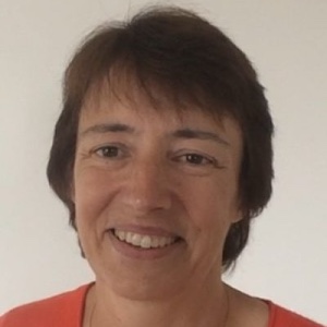 A smiling woman with short brown hair looks at the camera, standing in front of a plain white background.