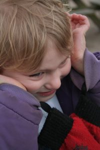 A child with their hands over their ears, which can be a sign of sensory overload in autistic people