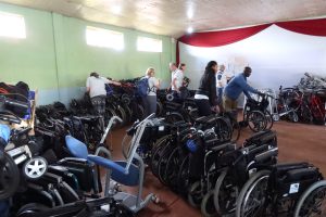 Photo of rows of wheelchairs, lined up ready to be distributed on the Wheels for the World mission in Kimilili. UK and local Kenyan team members are checking and organising the chairs.
