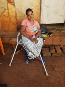 Juliet, a Ugandan lady, sits outside her house with her crutches, given to her last year by Through the Roof