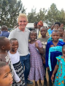 A UK volunteer with Through the Roof (Peter, the blog-writer), stood smiling with a group of happy Rwandan children, wearing their Sunday-best clothes and stood outside the church.