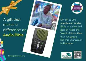 An e-card on a dark green background, with text on the left that says: 'A gift that makes a difference: an Audio Bible’ To the right are 2 photos: a close-up photo of a solar-powered audio Bible (which looks like a small mobile phone); a smiling young Rwandan man holding an Audio Bible up in the air, as he sits in a wheelchair. Below the images is text saying: 'My gift to you supplies an Audio Bible so a disabled person hears the Word of life in their own language - like this young man in Rwanda. There are logos for Through the Roof www.throughtheroof.org and their project Wheels for the World. There is also a QR code linking to their International Missions page at https://throughtheroof.org/international-mission/