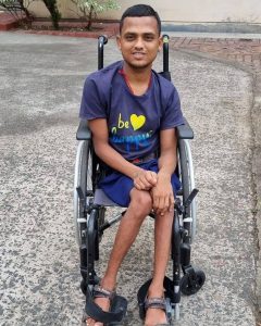 A young man age 28 in navy blue shorts and T shirt, sat in a wheelchair, smiling broadly!