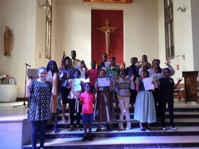 The choir of angels - about twenty people - standing in front of the altar at their church. They're holding certificates that indicate they've learned some sign language to include deaf members of the congregation in their worship.