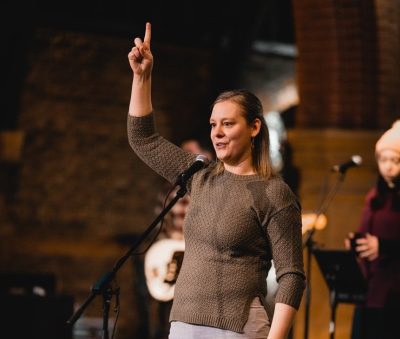 Janneke Klos in a church_she is doing the Makaton sign for God (pointing upwards)