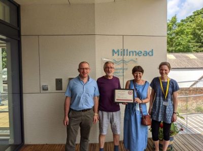Four members of the team at Guildford Baptist Church standing outside their new more accessible Milmead building, holding their Luke 5 certificate