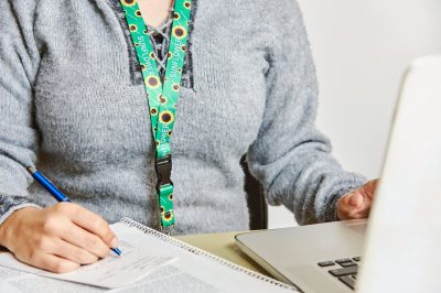 Woman studies or works using a sunflower lanyard, invisible disabilities symbol