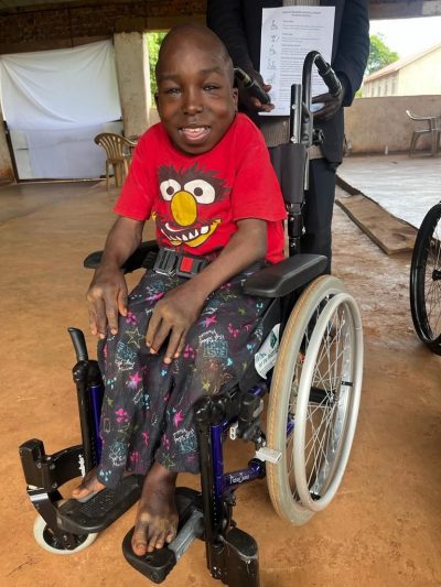 A child in a red t shirt in their new wheelchair