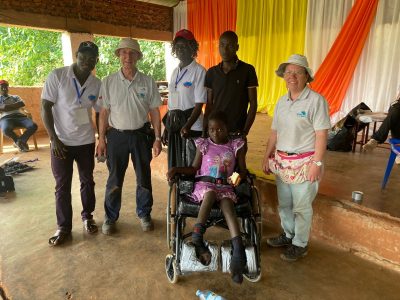 Team members and a young girl in her new wheelchair