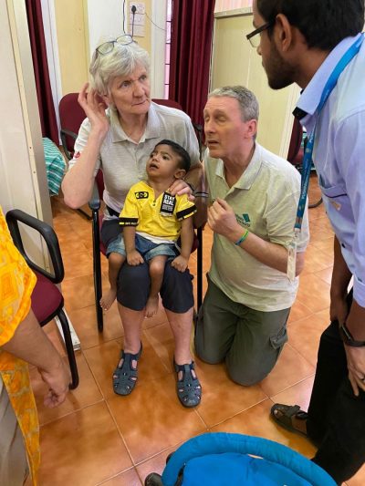 Two members of the wheels team talk with a young indian boy and his family to assess him for a new wheelchair