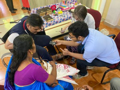 A member of the Indian hospital staff chats with a recipient and their partner while a Wheels team member takes notes