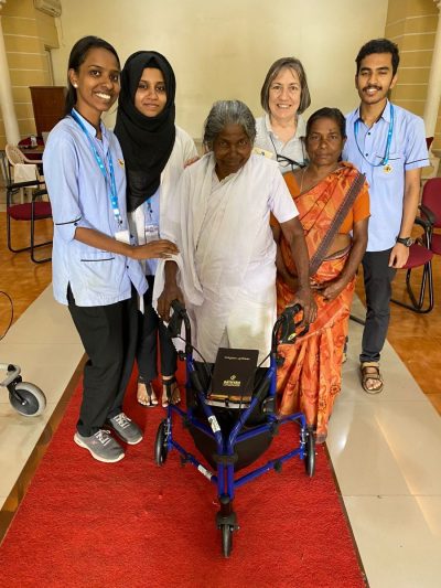 A recipient with their new mobility walker, supported by Indian hospital staff and a family member