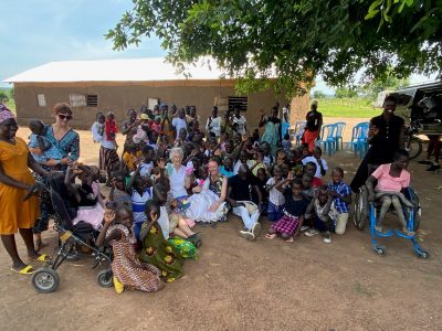 The wheels team sits and talks with a large group of local people, including some in wheelchairs and mobility buggies