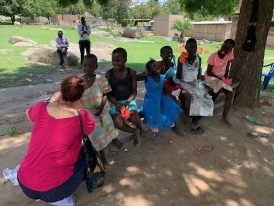 A member of the wheels team shares some puppets with a local family, in the shade of a tree