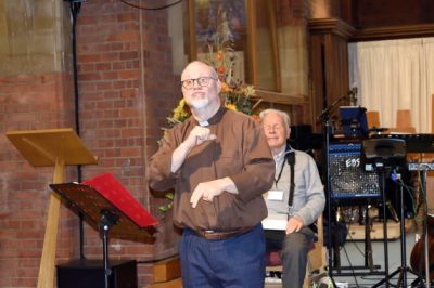 Neil Robinson presents his talk at the front of St Georges in Ashtead. He's signing in BSL.