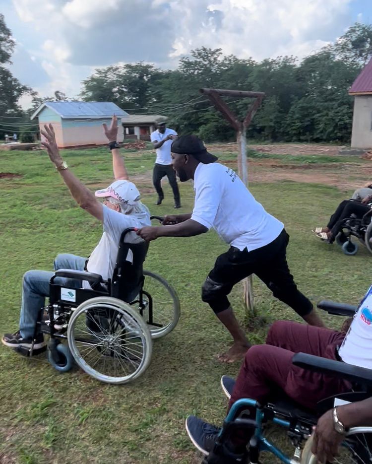 The team wheelchair races, as one team member celebrates crossing the line while another pushes them