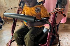a child in a yellow football top sits in his new walker