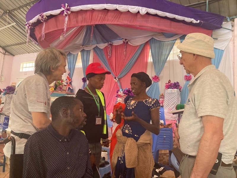 Samuel K, a young man who is being fitted for a wheelchair, and his mother, who is talking to the UK volunteers through a local interpreter.