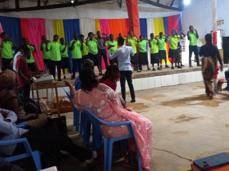 A group of people all in the same yellow-green tshirt singing together on the stage