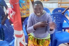 A young disabled girl in a purple jumper sits