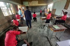 Several students in red jumpers sat around in the school room
