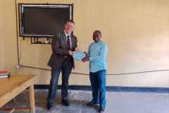Trevor, a member of the UK team is handed a certificate by Enos, another member of the team