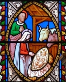 A stained glass window showing a Nativity scene of baby Jesus, Mary and Joseph and animals, in a stable