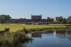 Ashburnham Place, a stately home overlooking green grounds, with a lake at the front of the picuter