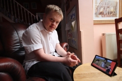 A young man with Down Syndrome, watching the Bible series Superbook with sign language