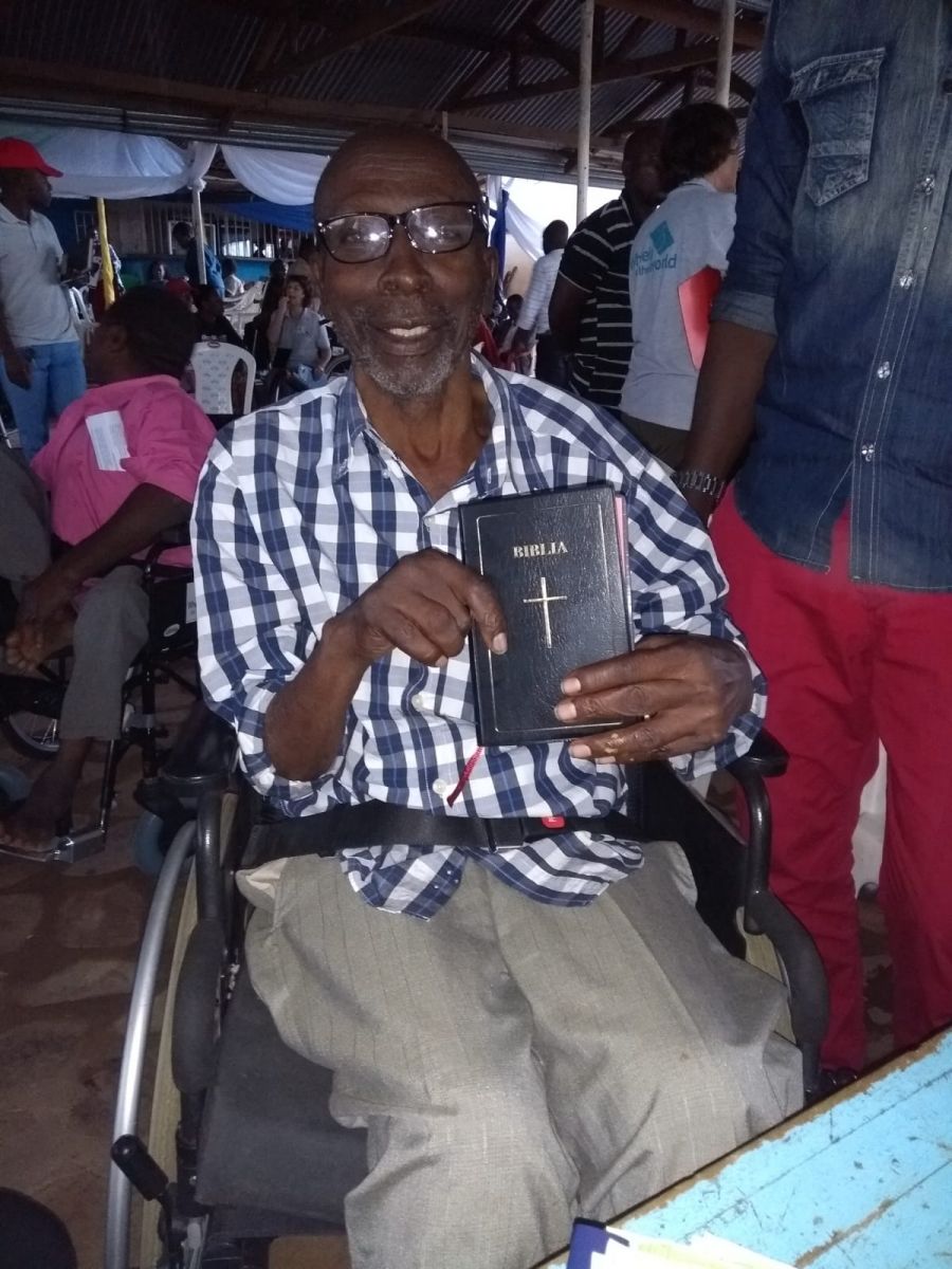 Mkama sat in his new wheelchair, holding his new Bible