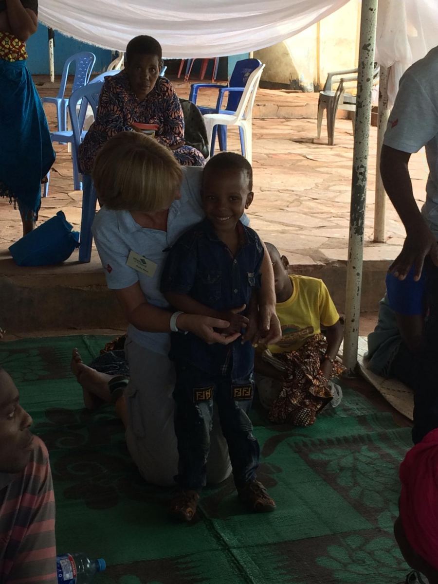 A young boy standing in the training centre with Kathy, a physio from the Wheels team