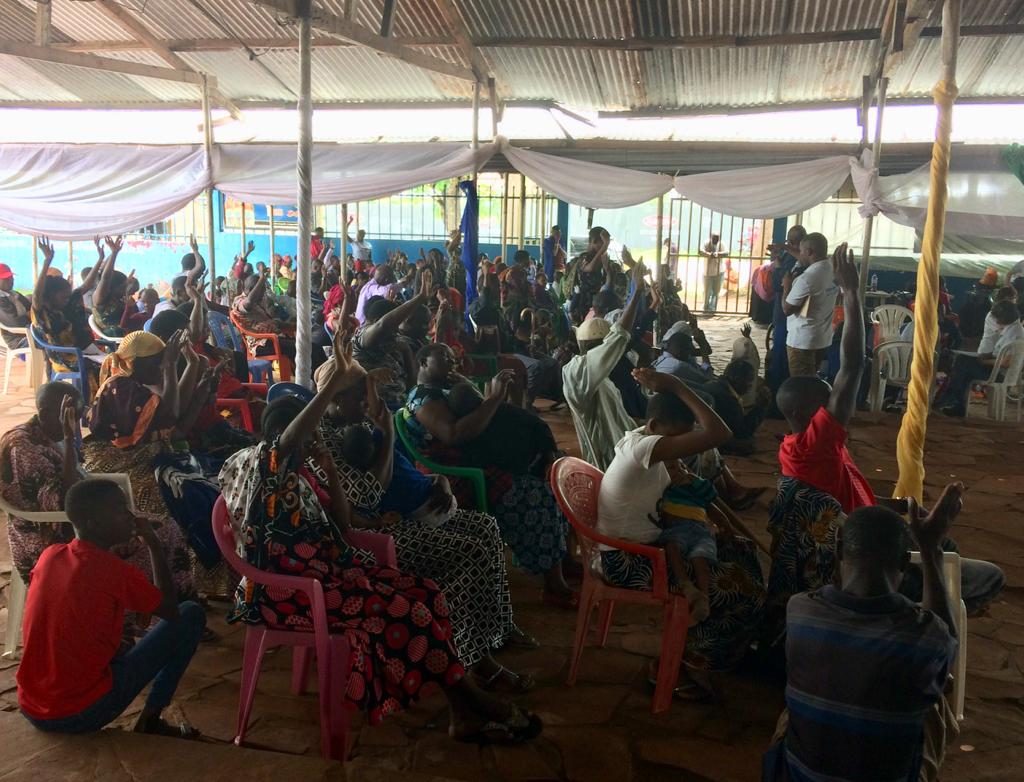 A crowd at the workshop with many raising their hands to respond