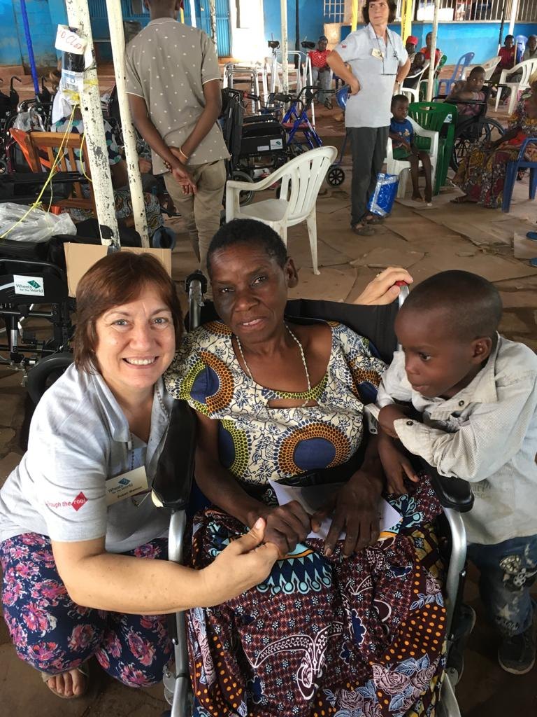 A lady in her new wheelchair with a child and one of the wheels team