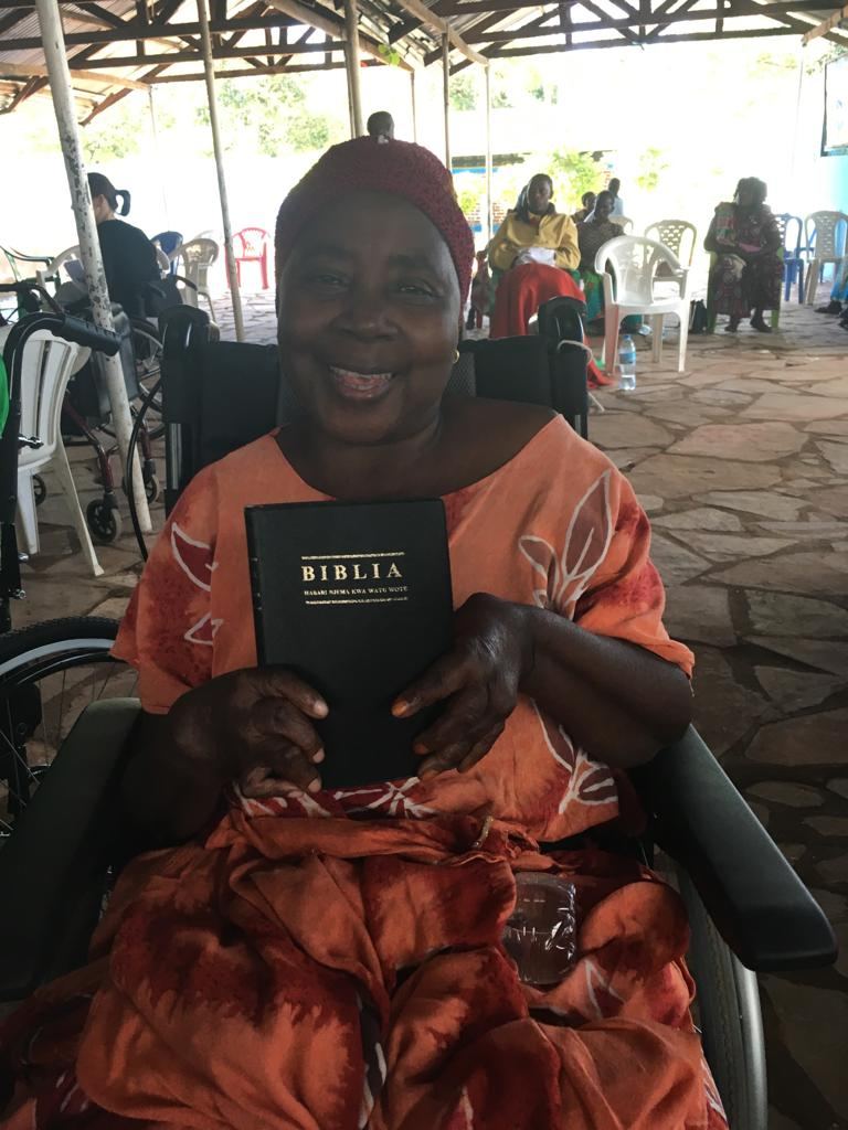 A  young woman in her new wheelchair, holding a Bible