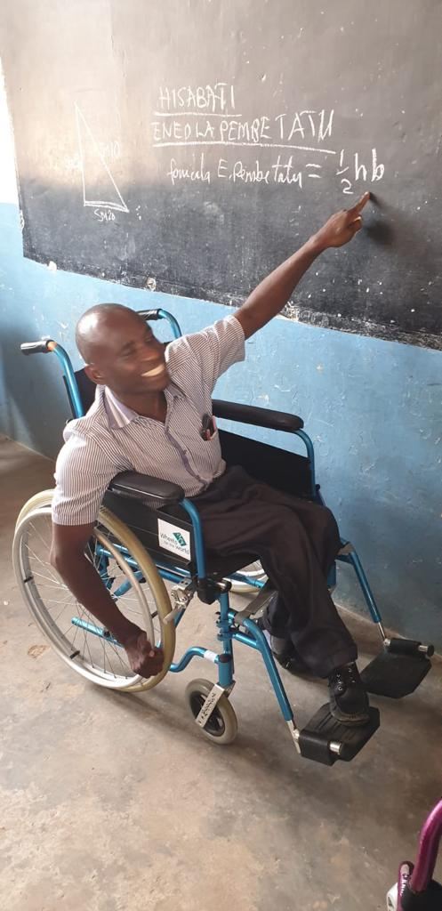 Maghembe in his new chair, pointing at the blackboard