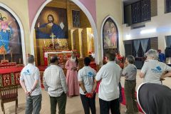 The wheels team is gathered around the alter at a church, listening to someone from the local Indian team talking
