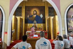The wheels team is gathered around the alter at a church, listening to someone from the local Indian team talking