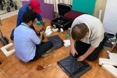 A member of the wheels team and a member of the hospital team cut and adjust some wheelchair padding