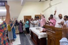 Members of the Indian church holding their hands up, praying and singing