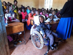 Dylan, a young boy in a supportive wheelchair, sits towards the front of a full church meeting