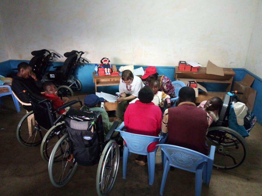 a couple of members of the team and several wheelchair recipients pray together