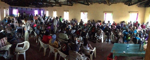 A crowd of people gathering for a wheelchair fitting