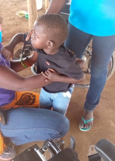 A little girl being helped with a wheelchair fitting