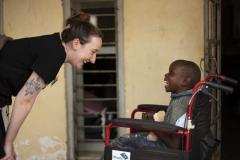 One of the team laughs with a child in their new wheelchair