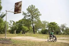 A young boy in a new wheelchair wheels across a basketball court